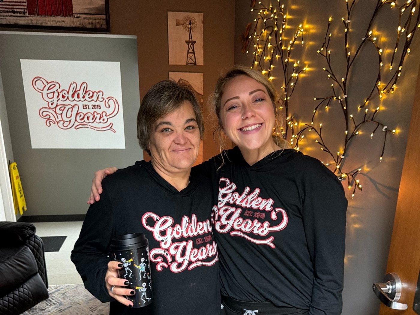 Two Golden Years staff members in branded shirts sharing a warm moment